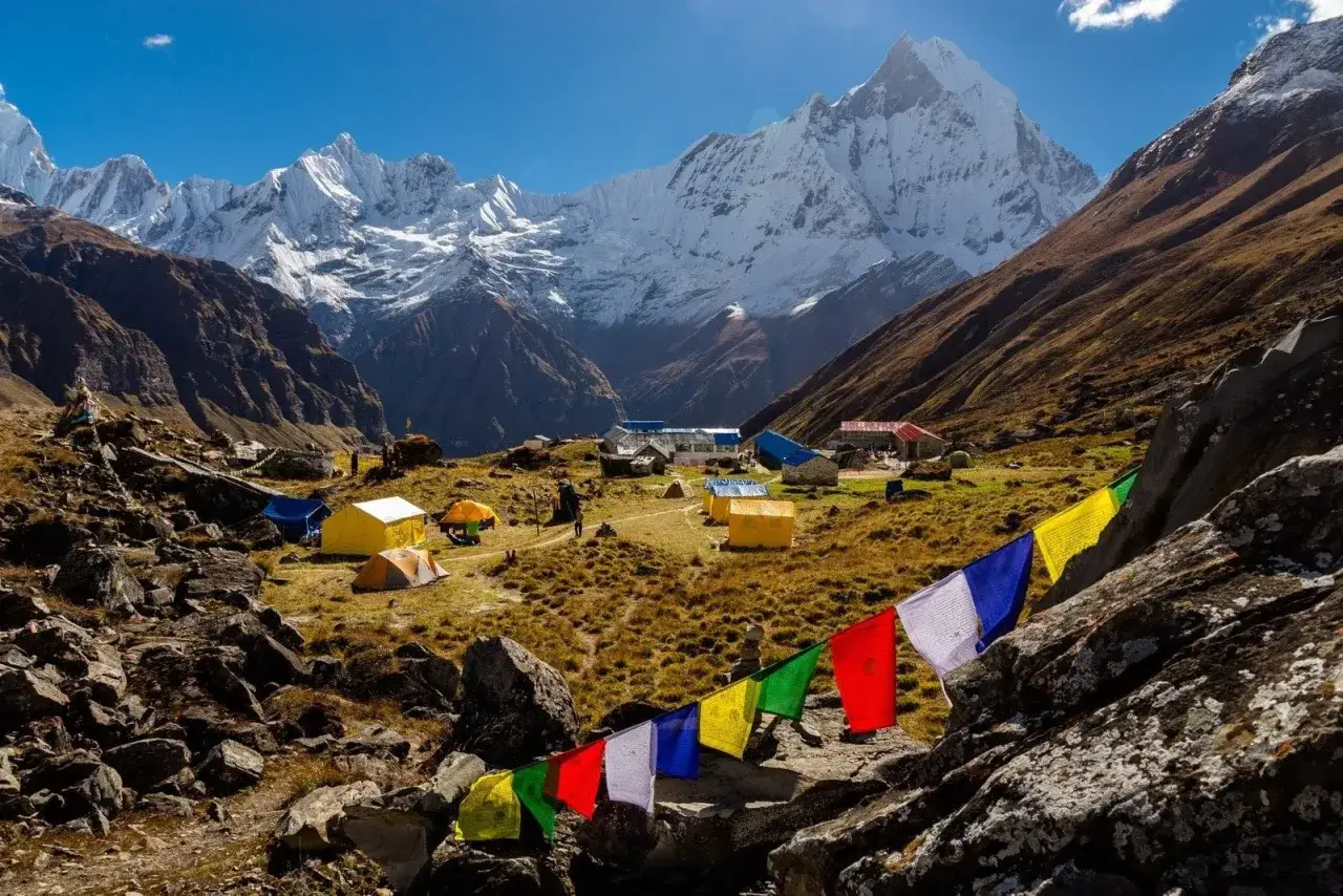 Kolorowe flagi modlitewne powiewają na tle obozu namiotowego i ośnieżonych szczytów podczas Annapurna Circuit Trek.