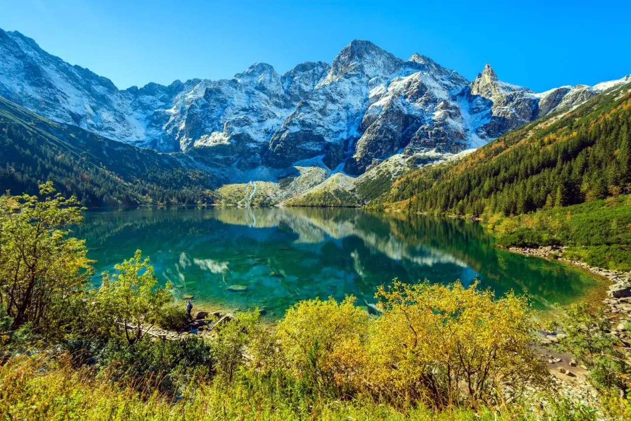Piękne Morskie Oko, idealne na trasę spacerową. Lśniąca tafla wody odbija ośnieżone szczyty Tatr i jesienne lasy.