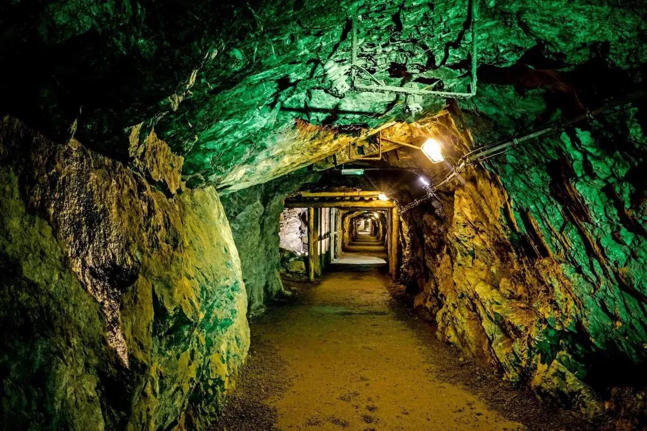 Wydobycie w Górach Złotych: oświetlony tunel kopalni, zielone i żółte skały, drewniane wsporniki. Atrakcje podziemne.