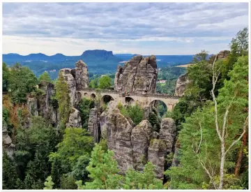 Kamienny most Bastei w Szwajcarskiej Saksonii, łączący skalne baszty pośród zielonych lasów i malowniczych gór.