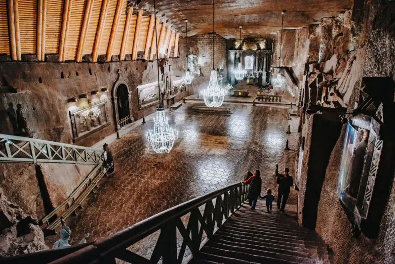 Rodzina schodzi schodami do podziemnej kaplicy w kopalni soli. Zwiedzanie Wieliczki to niezapomniane przeżycie.