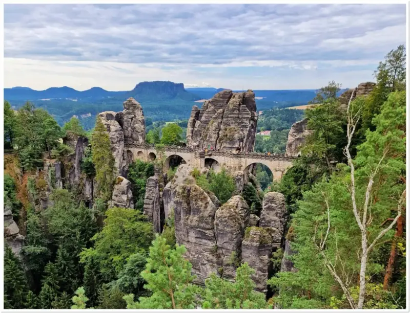 Kamienny most Bastei w Szwajcarskiej Saksonii, łączący skalne baszty pośród zielonych lasów i malowniczych gór.